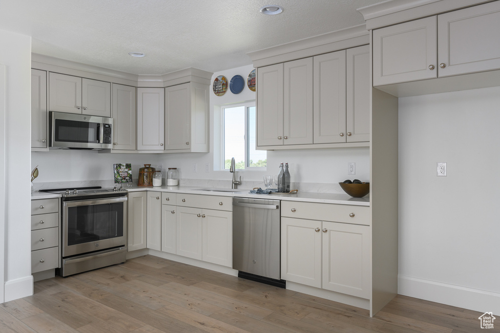 Kitchen featuring recessed lighting, light countertops, a sink, light wood finished floors, and stainless steel appliances