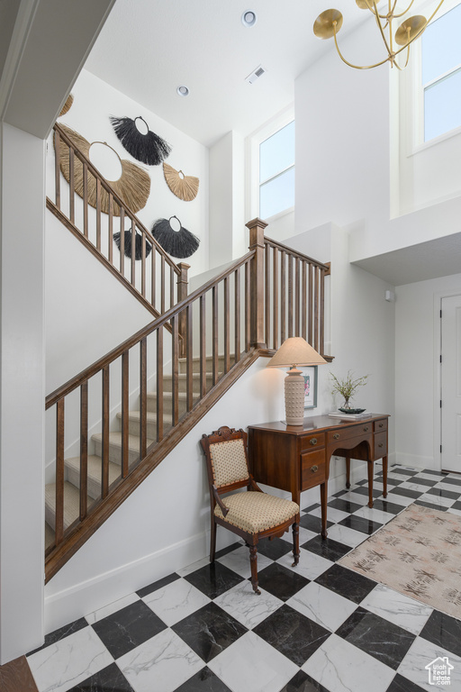 Stairs with a healthy amount of sunlight, baseboards, visible vents, and a towering ceiling