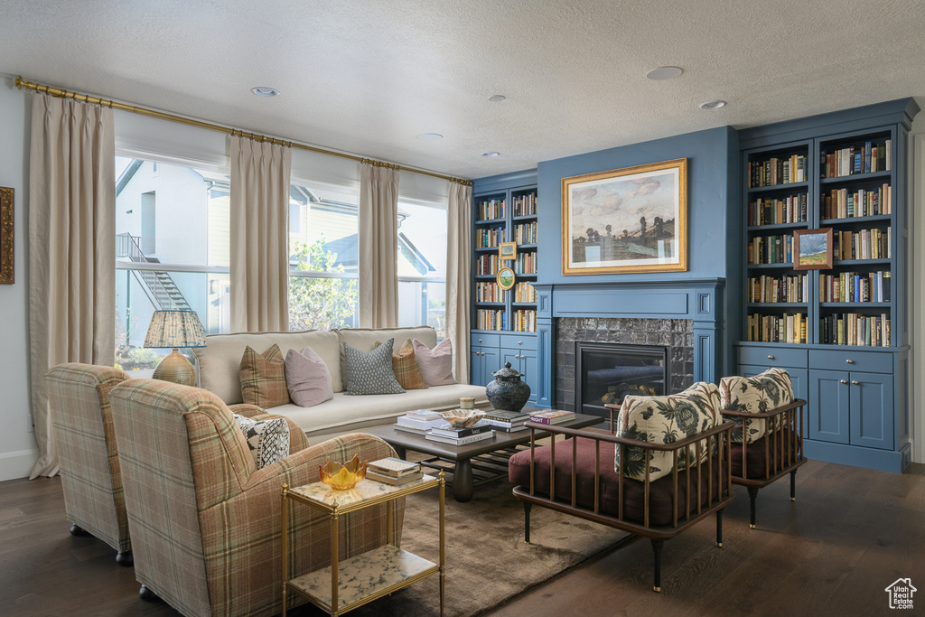 Living area featuring a textured ceiling, dark wood-style flooring, a wealth of natural light, and a premium fireplace