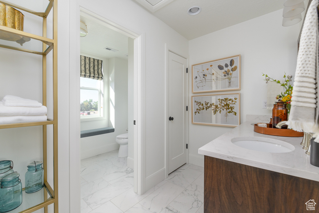 Bathroom with baseboards, visible vents, toilet, and marble finish floor