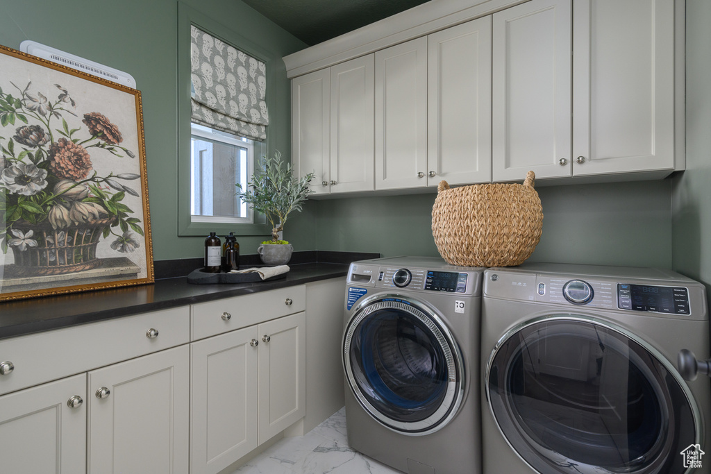 Washroom featuring marble finish floor, cabinet space, and washing machine and clothes dryer