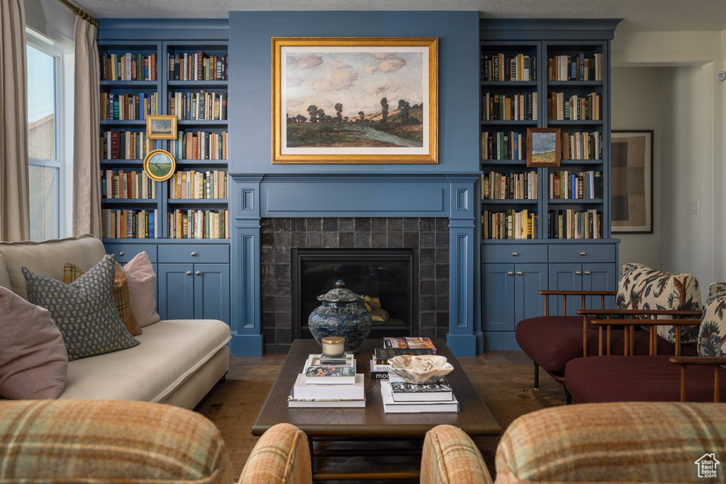 Sitting room featuring built in features, a tile fireplace, and wood finished floors