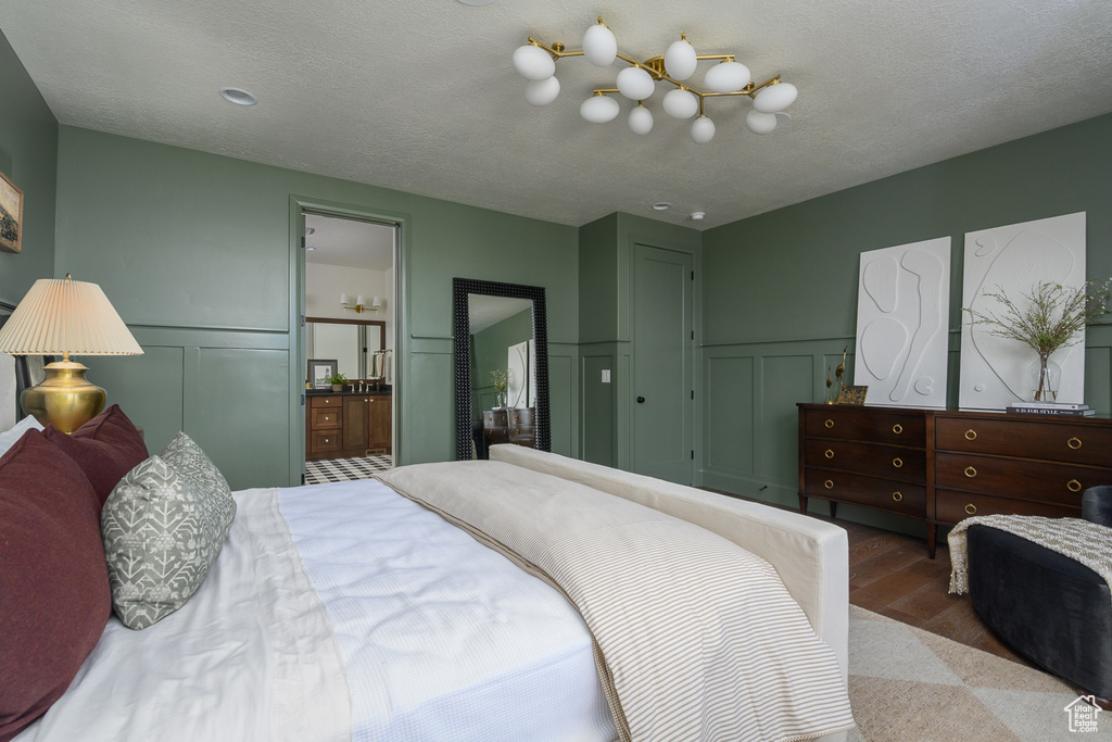 Bedroom with a wainscoted wall, a decorative wall, and wood finished floors