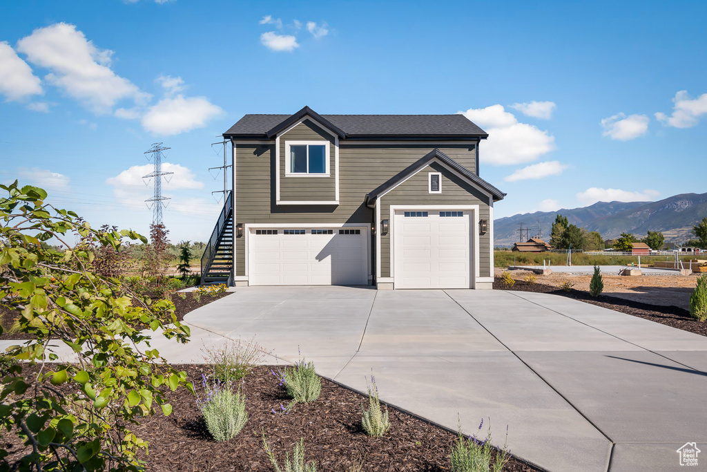 Traditional-style house with a garage, fence, a mountain view, driveway, and stairway
