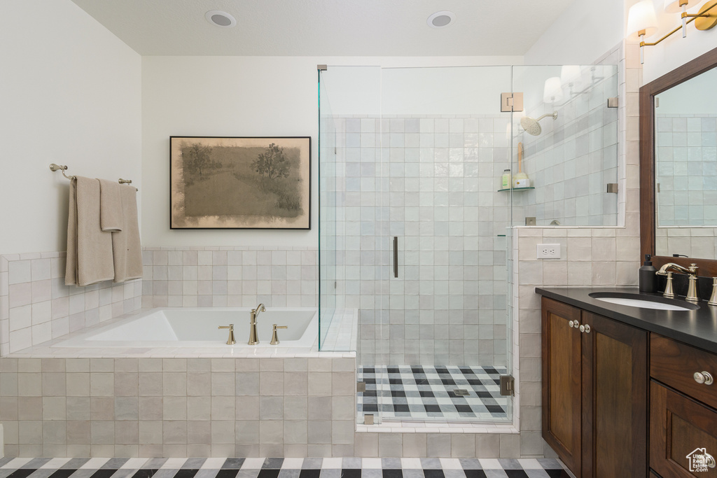 Full bathroom featuring a shower stall, a bath, and vanity