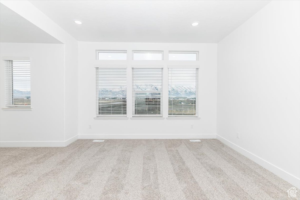 Carpeted spare room with a healthy amount of sunlight, baseboards, and recessed lighting