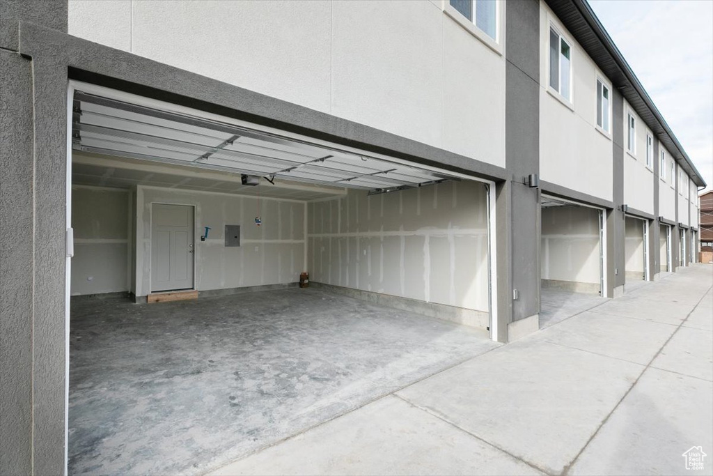 Garage with driveway, a garage door opener, and electric panel