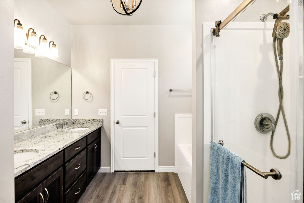 Full bath with a sink, double vanity, walk in shower, and wood finished floors