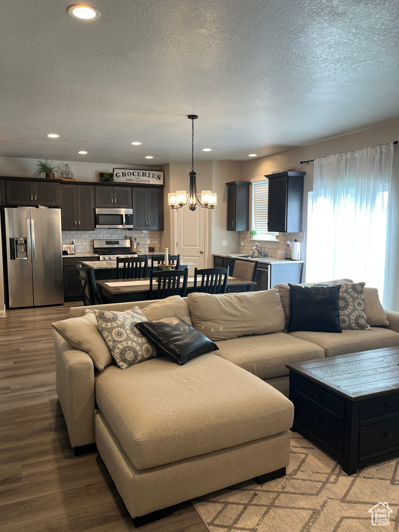 Living room with light wood-style floors, recessed lighting, a textured ceiling, and a notable chandelier