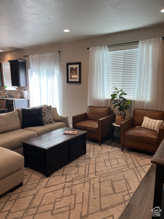 Living room with recessed lighting, a textured ceiling, and light wood-type flooring