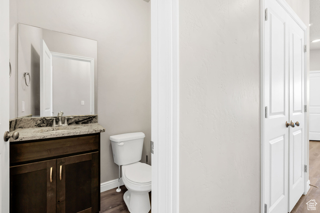 Bathroom with vanity, baseboards, toilet, and wood finished floors