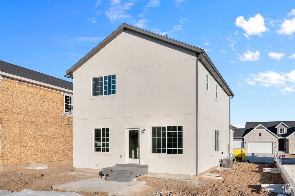 Rear view of property with stucco siding and central AC