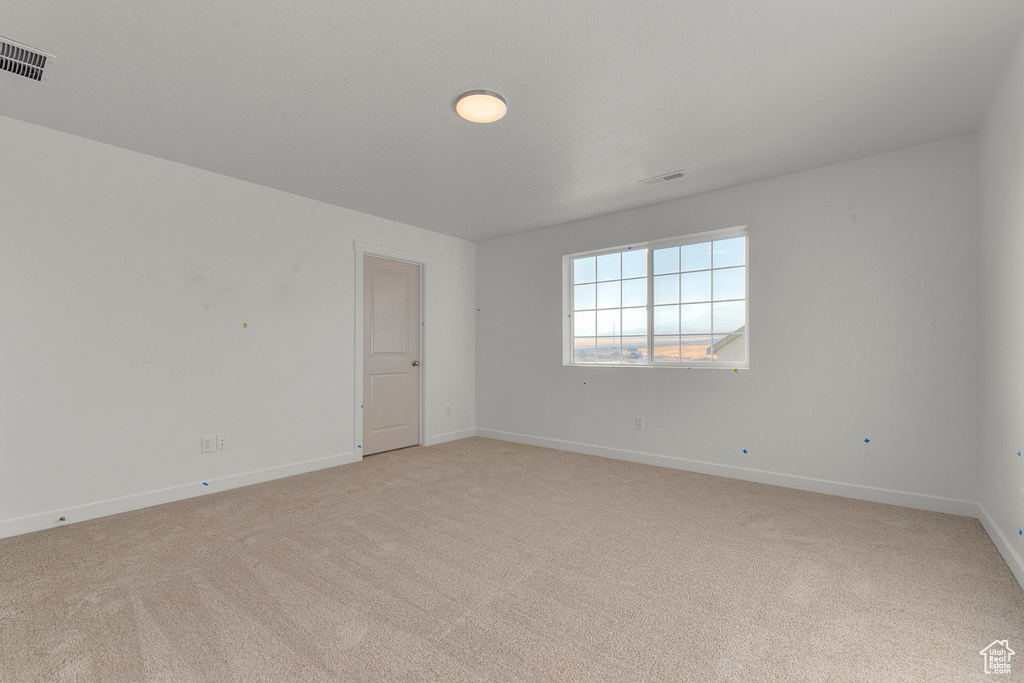 Spare room featuring baseboards, visible vents, and light colored carpet