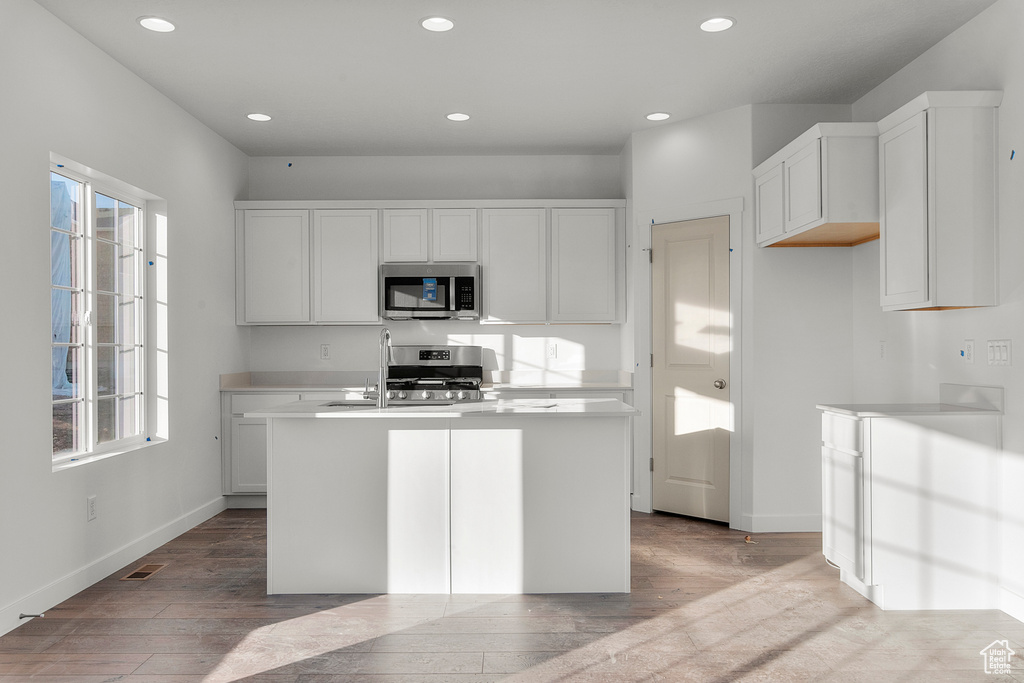 Kitchen with a kitchen island with sink, visible vents, baseboards, stainless steel appliances, and recessed lighting