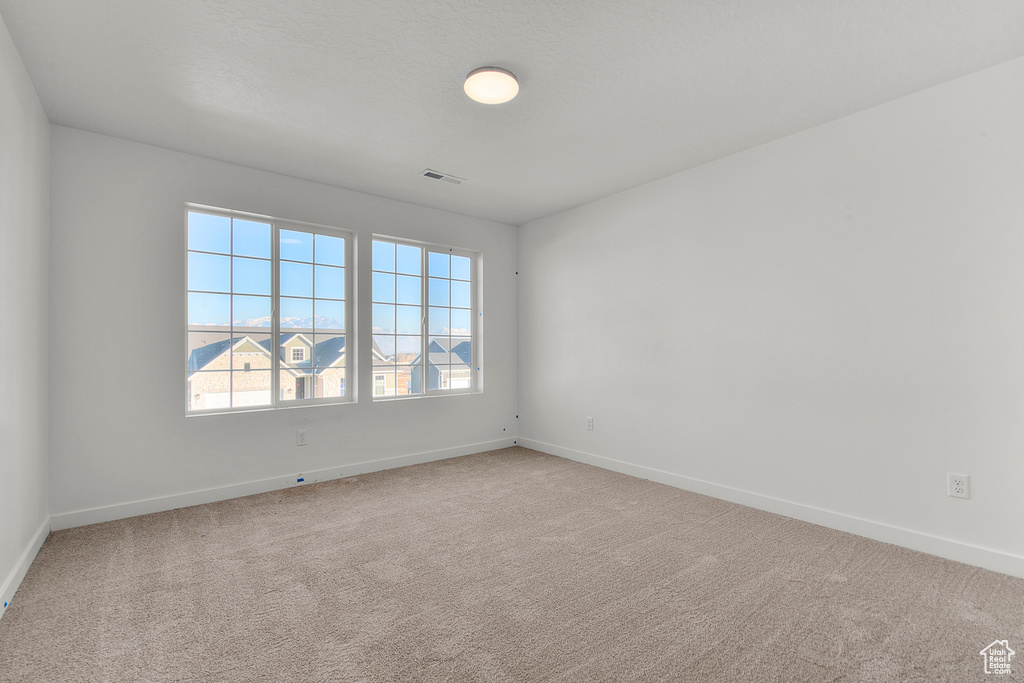 Carpeted empty room with baseboards and visible vents