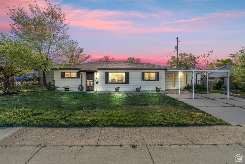 Bungalow featuring a yard, concrete driveway, and a carport