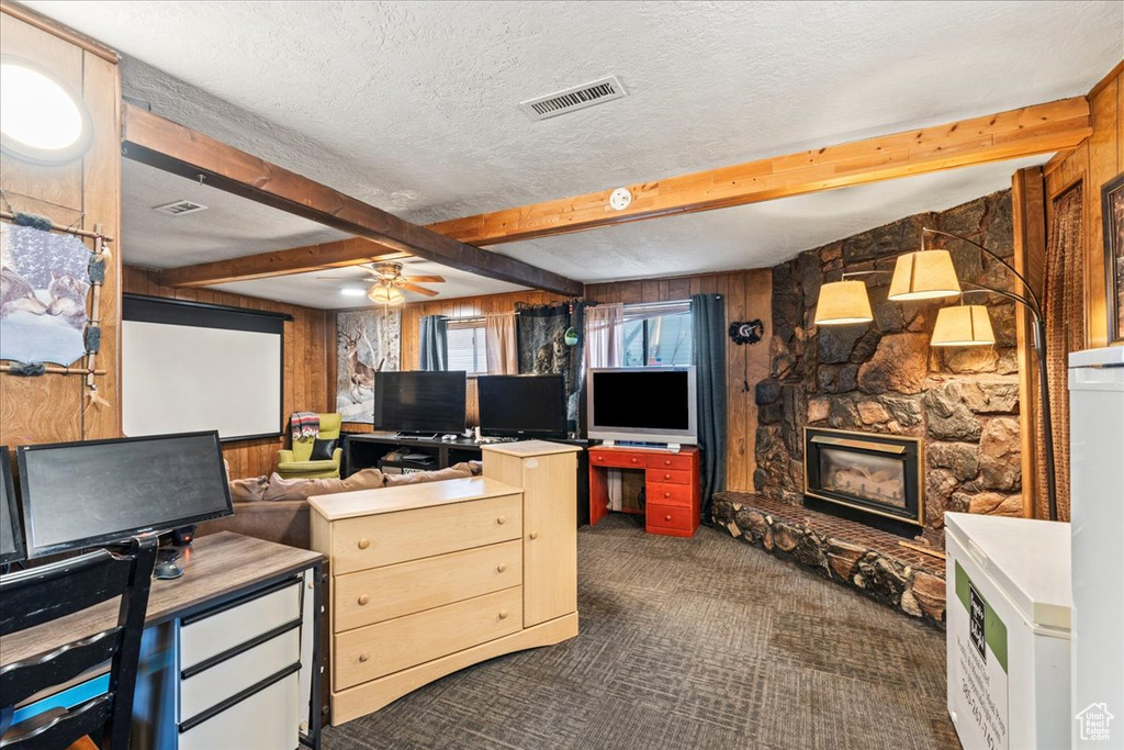 Living area with a ceiling fan, visible vents, beam ceiling, and dark colored carpet
