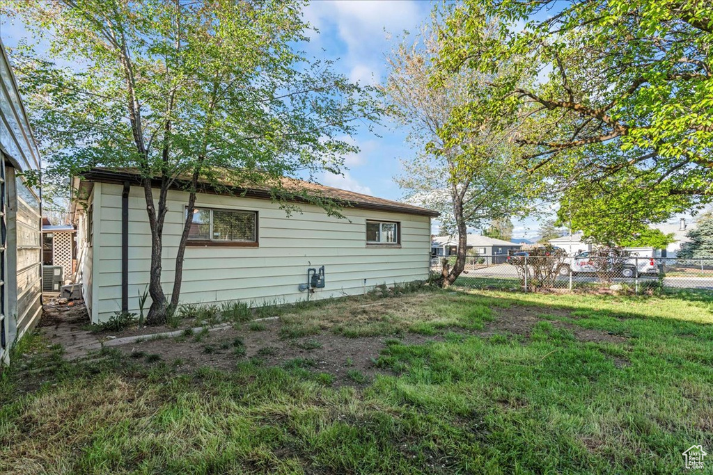 Rear view of property with fence, central air condition unit, and a yard