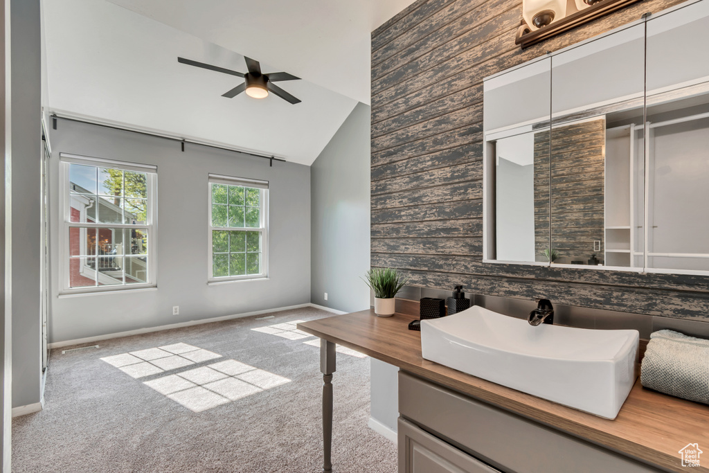 Bathroom with ceiling fan, a sink, baseboards, and high vaulted ceiling