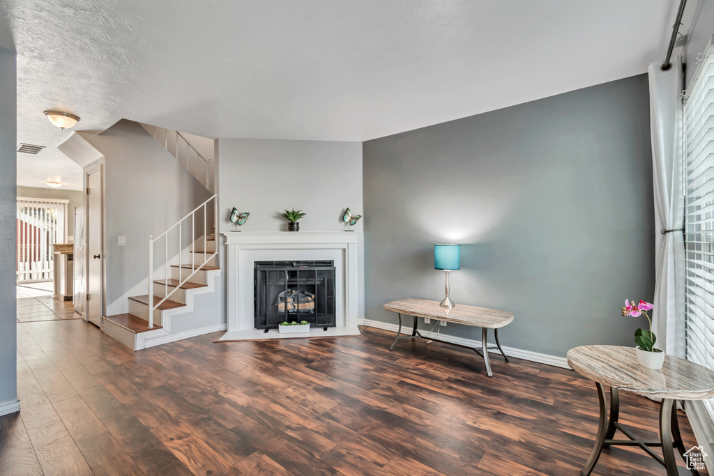 Living area featuring visible vents, wood finished floors, baseboards, stairway, and a fireplace with flush hearth