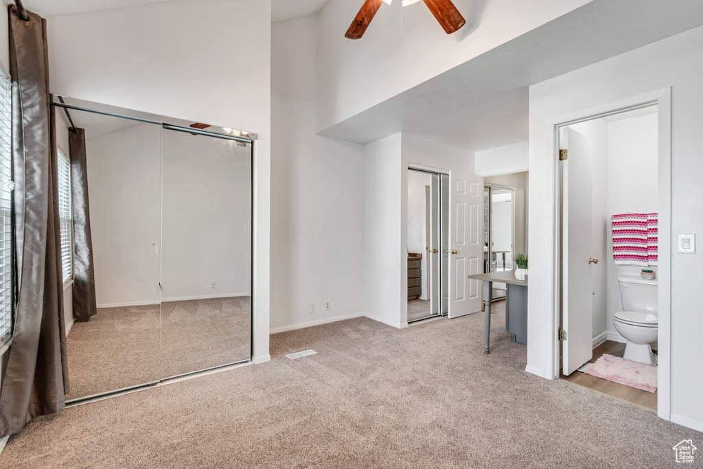 Unfurnished bedroom featuring carpet floors, two closets, a ceiling fan, baseboards, and ensuite bathroom