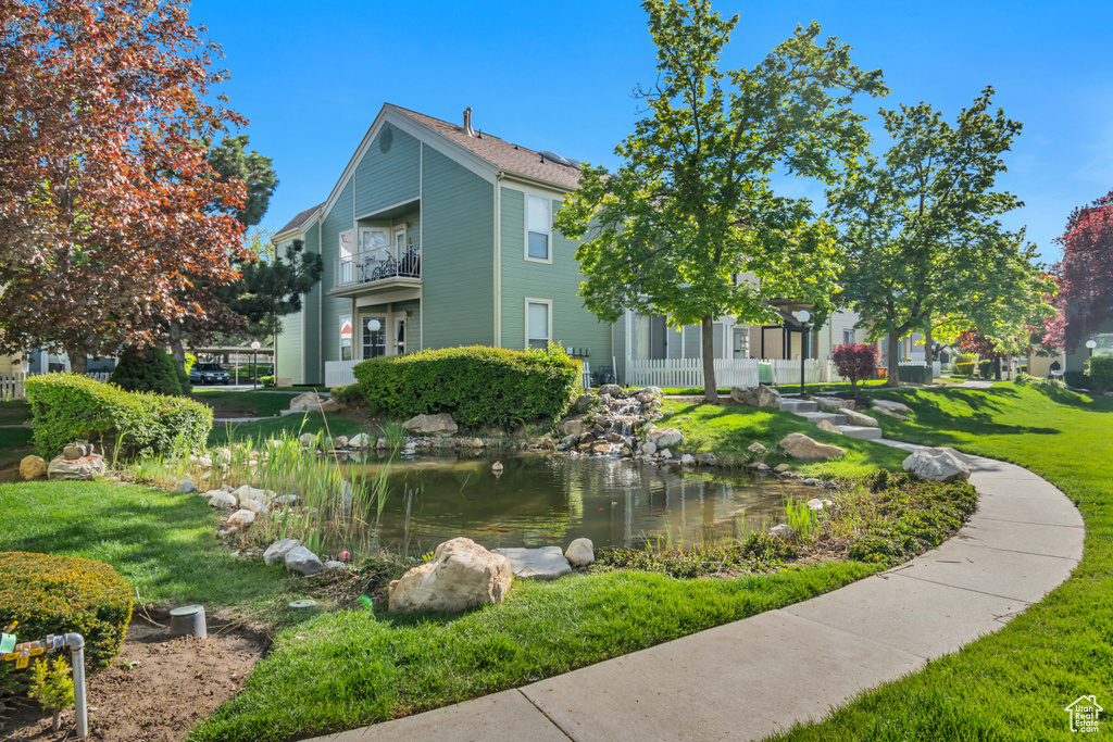 View of property's community featuring a small pond and a yard