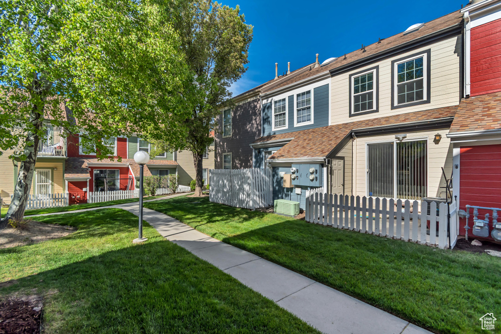 Rear view of property with a yard, fence, central AC unit, and roof with shingles