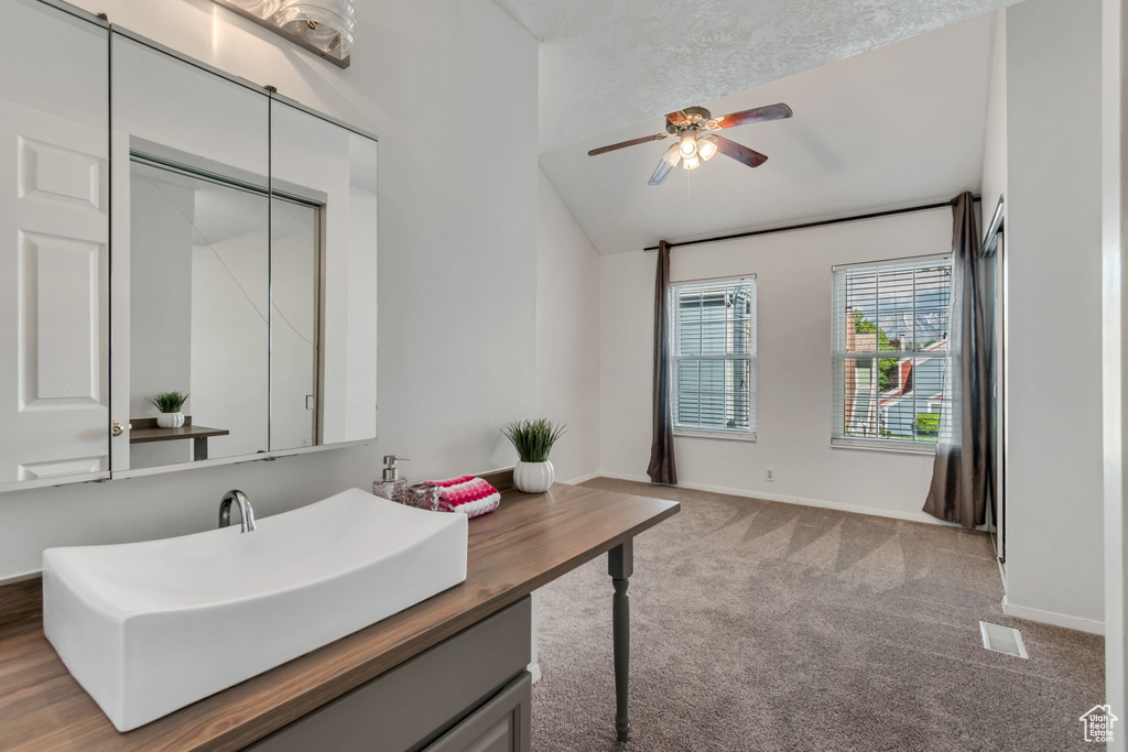 Bathroom with visible vents, vanity, a ceiling fan, baseboards, and vaulted ceiling
