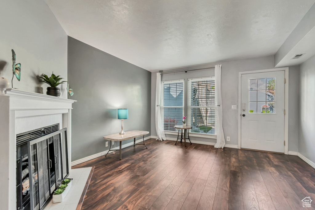 Entryway with baseboards, visible vents, wood finished floors, and a fireplace