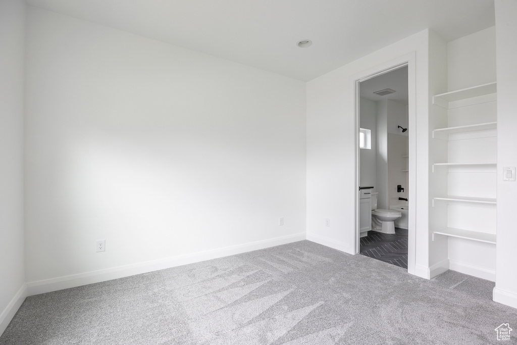 Unfurnished bedroom featuring baseboards, carpet, and ensuite bathroom