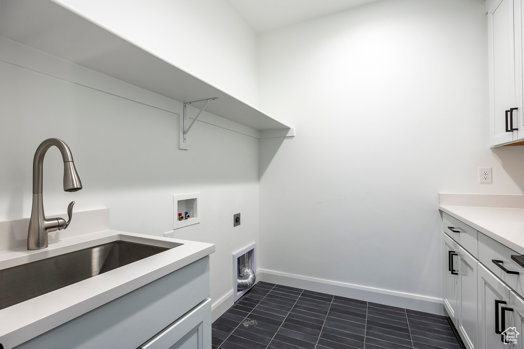 Clothes washing area with cabinet space, washer hookup, a sink, baseboards, and electric dryer hookup