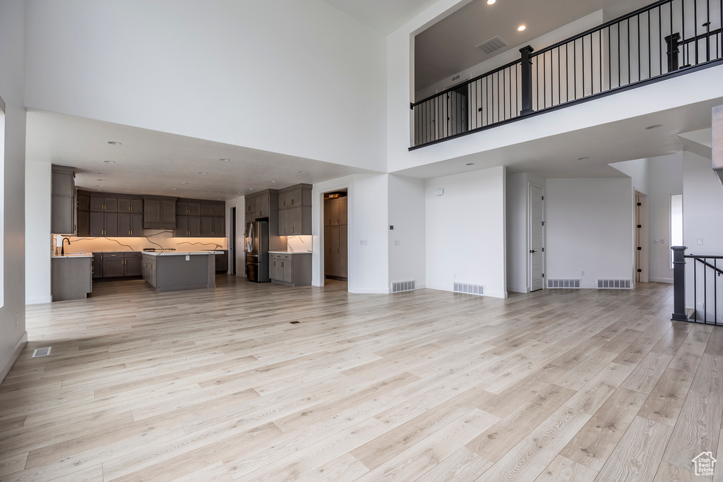 Unfurnished living room with visible vents and a towering ceiling