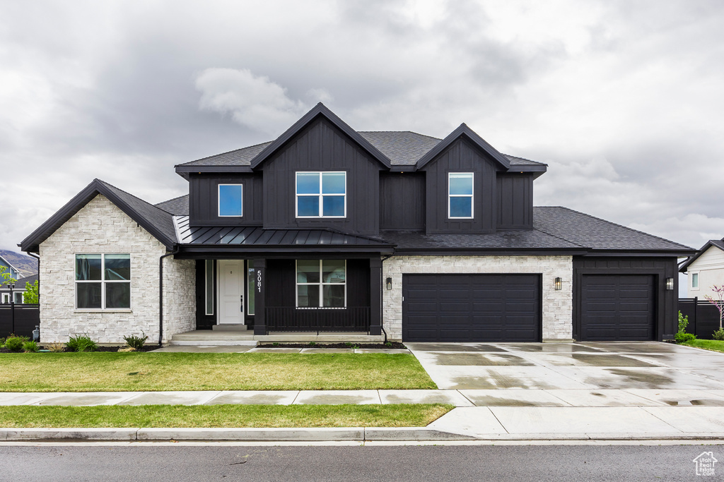 Craftsman inspired home featuring covered porch, board and batten siding, a front yard, concrete driveway, and stone siding