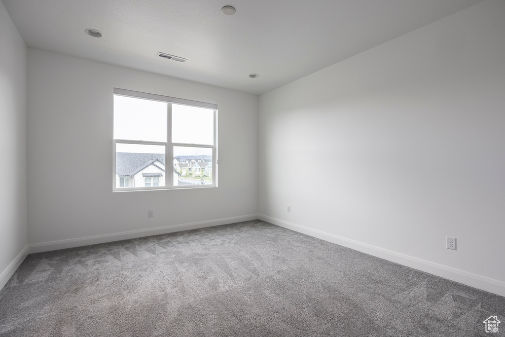 Spare room featuring baseboards, carpet, and visible vents