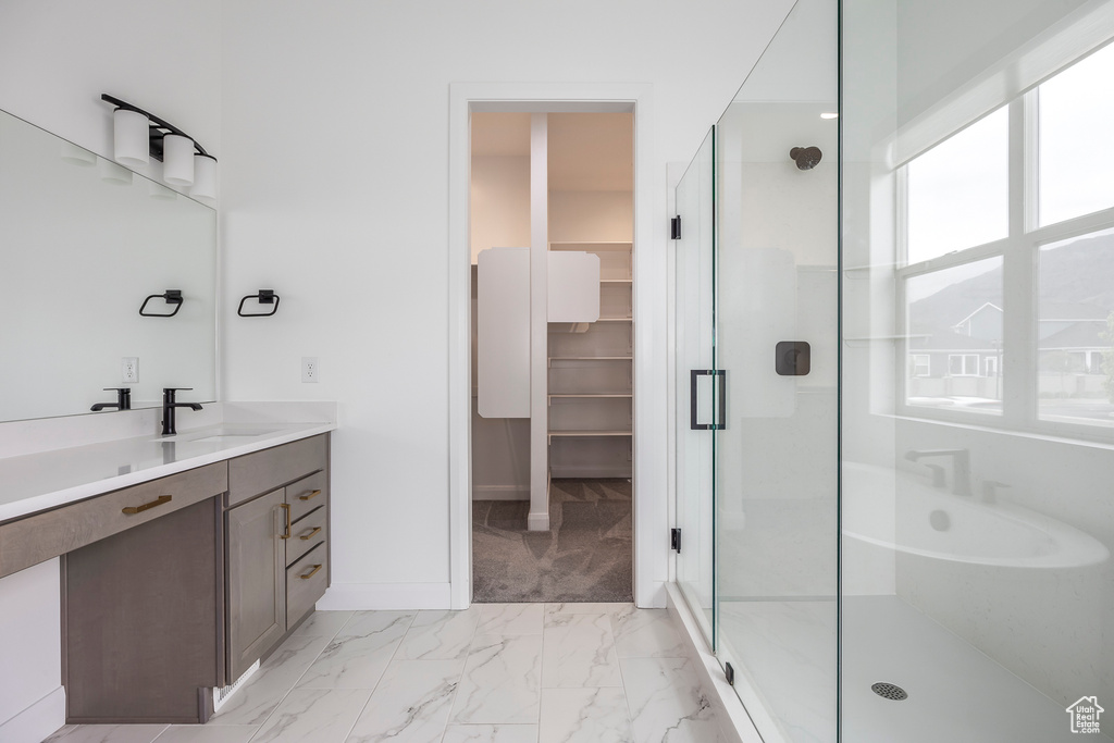 Full bath with vanity, marble finish floor, a walk in closet, and a shower stall