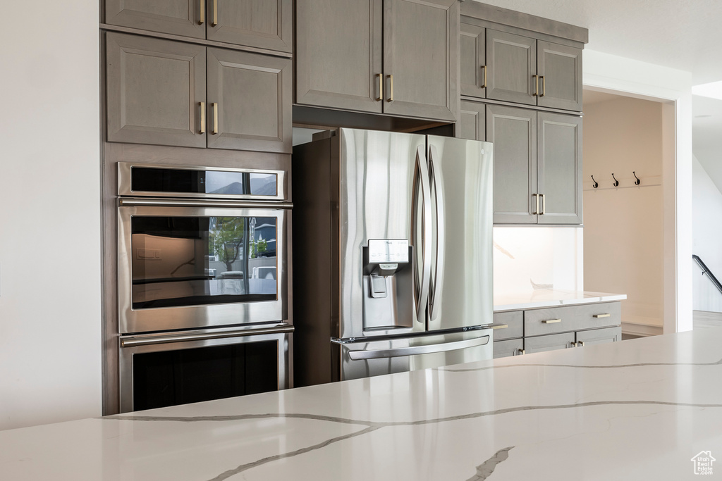 Kitchen with stainless steel appliances, light stone counters, and gray cabinets