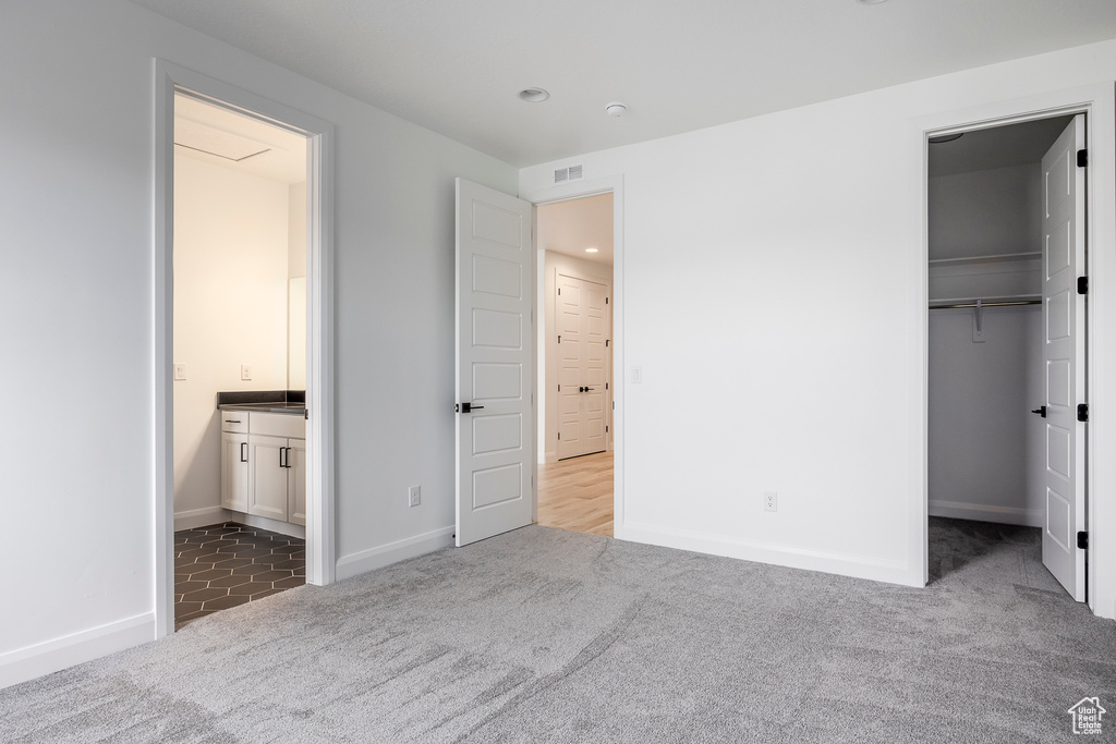 Unfurnished bedroom with visible vents, carpet flooring, baseboards, and a walk in closet