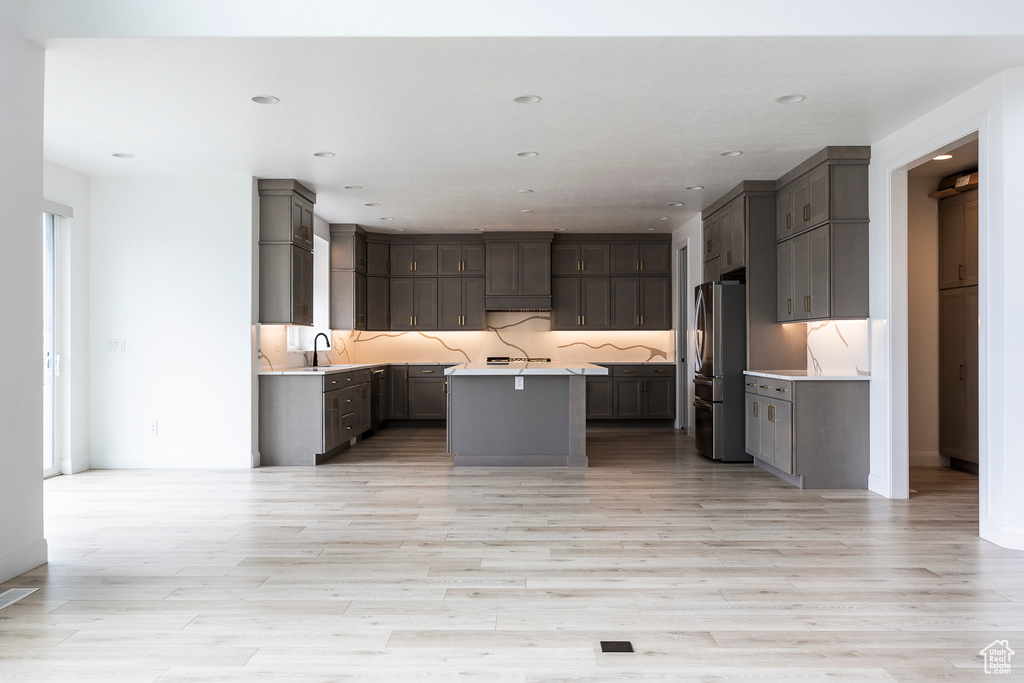 Kitchen featuring freestanding refrigerator, a kitchen island, light wood-style flooring, and light countertops