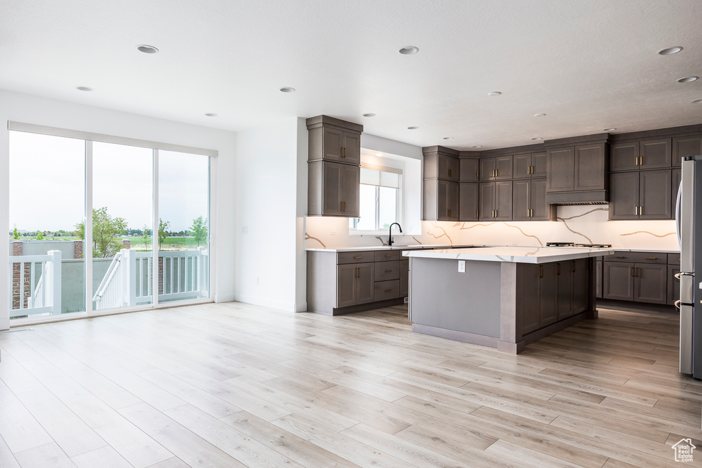 Kitchen with light wood-style floors, recessed lighting, a center island, appliances with stainless steel finishes, and backsplash