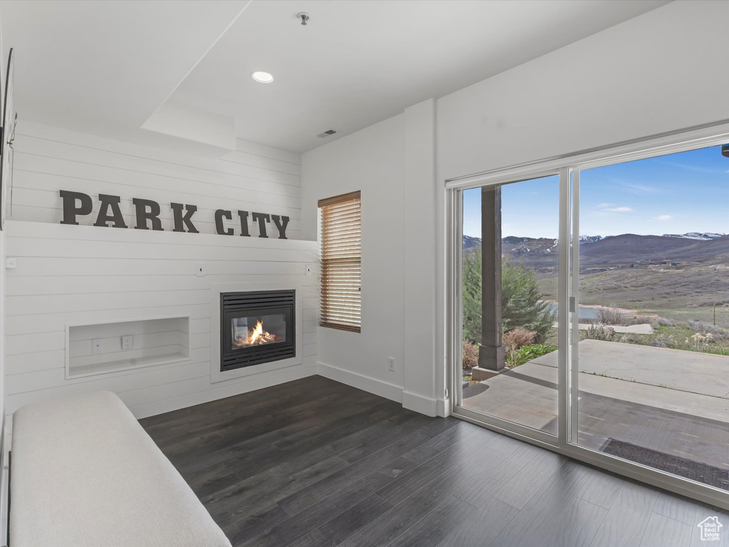Unfurnished living room featuring baseboards, a mountain view, dark wood-style floors, a glass covered fireplace, and recessed lighting