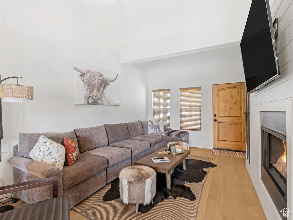 Living room with light wood-style floors and a warm lit fireplace