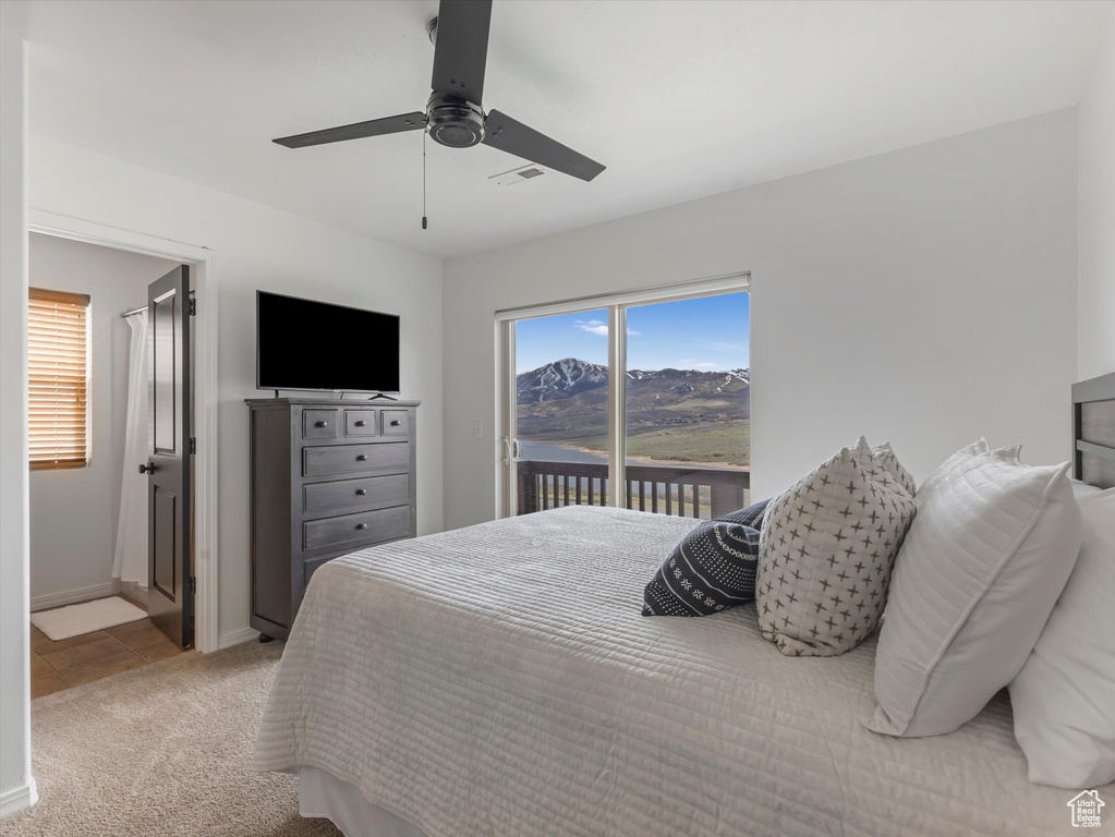 Carpeted bedroom featuring ceiling fan, access to exterior, baseboards, tile patterned floors, and ensuite bath