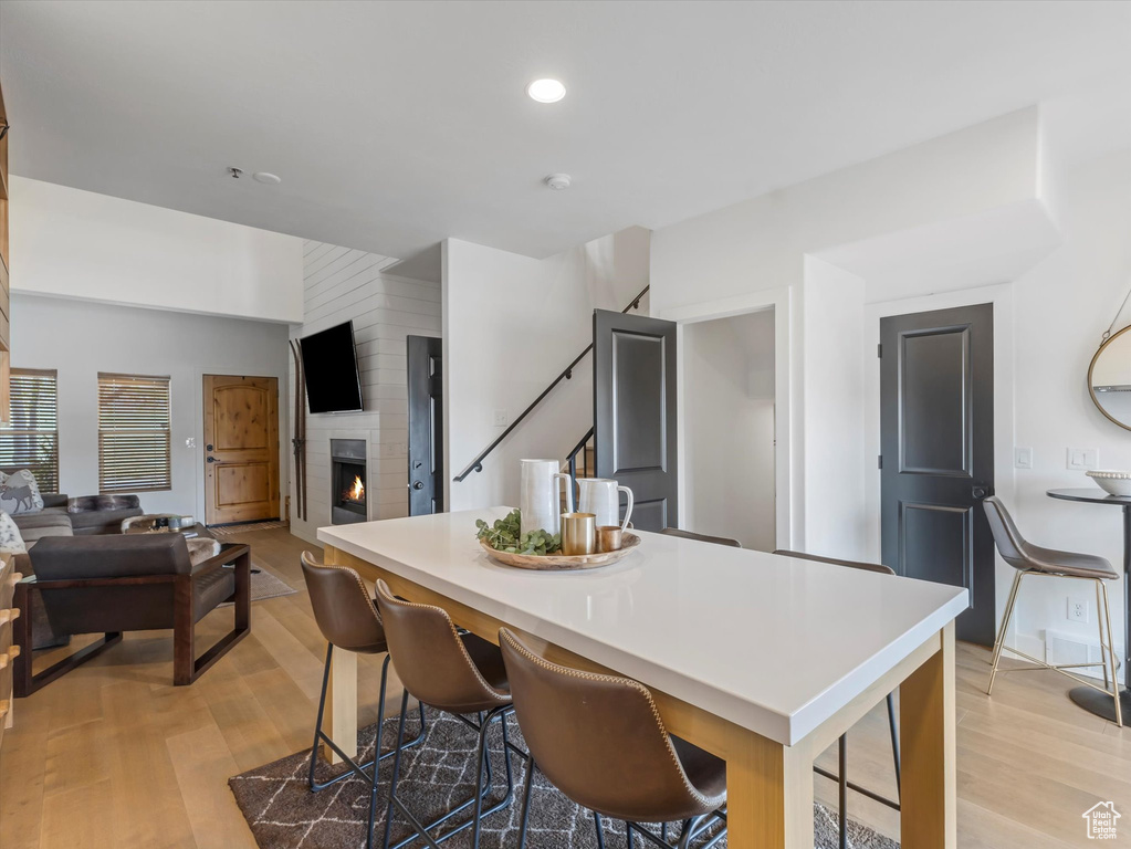 Kitchen with light countertops, a fireplace, light wood-type flooring, and open floor plan
