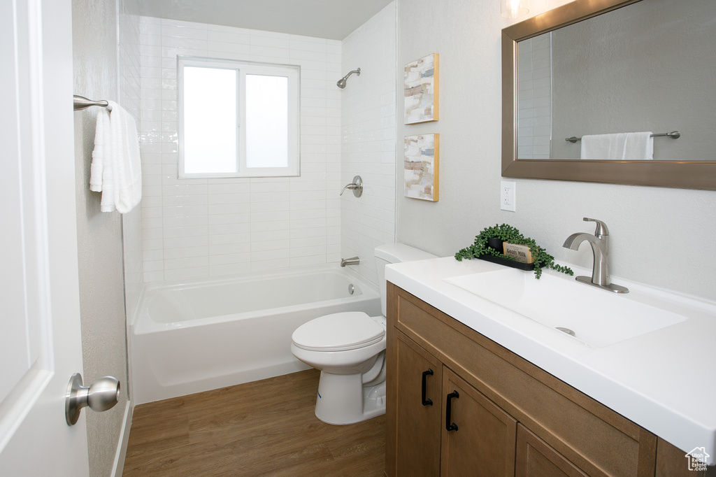 Full bathroom with vanity, wood finished floors, bathing tub / shower combination, and toilet