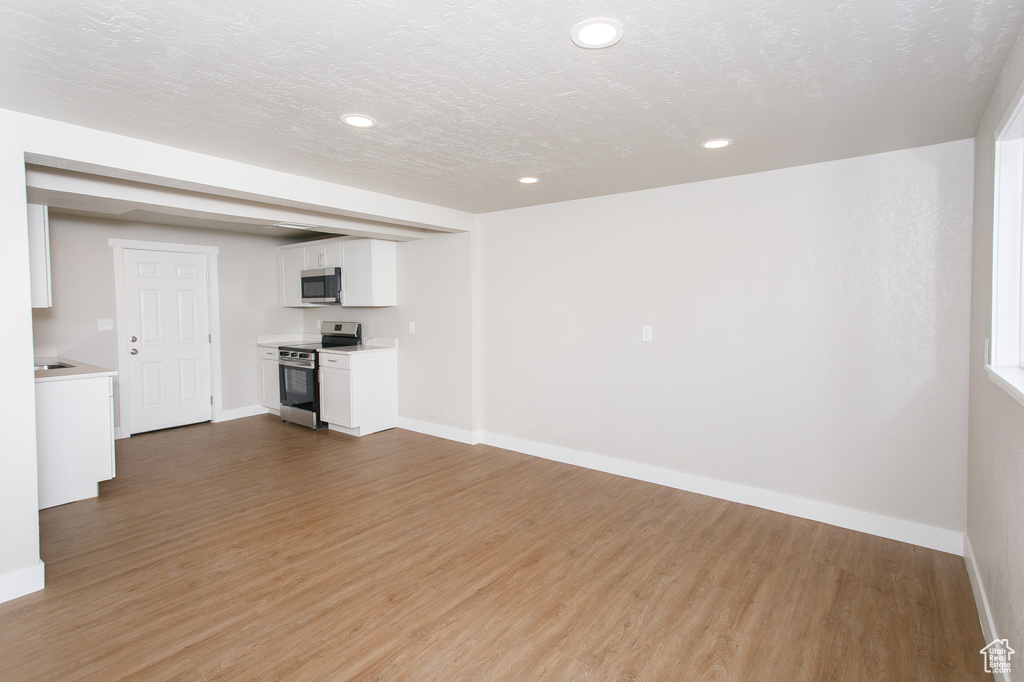 Unfurnished living room with recessed lighting, baseboards, and wood finished floors
