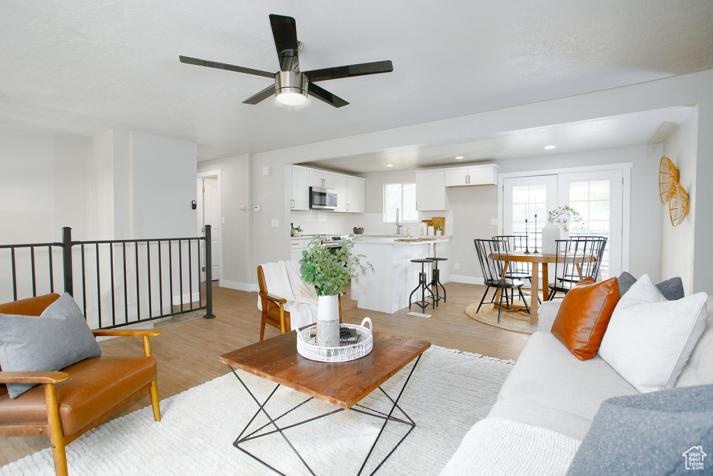 Living room with light wood-style floors, baseboards, a ceiling fan, and recessed lighting