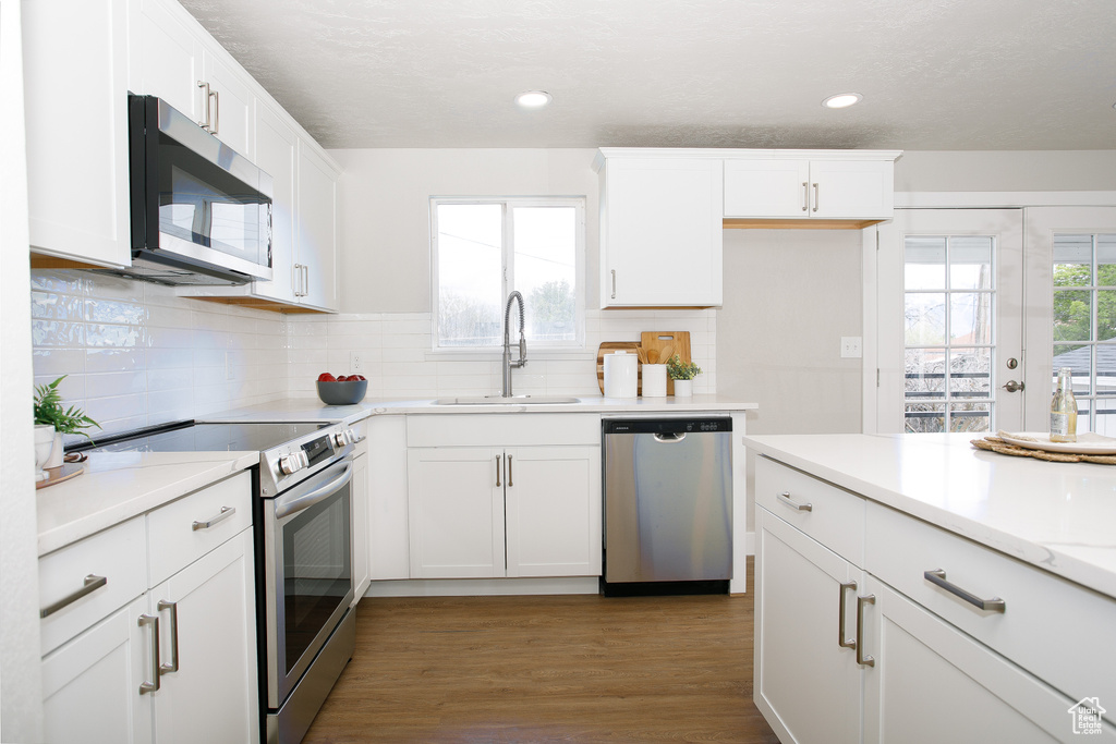 Kitchen featuring white cabinets, a sink, light countertops, stainless steel appliances, and backsplash