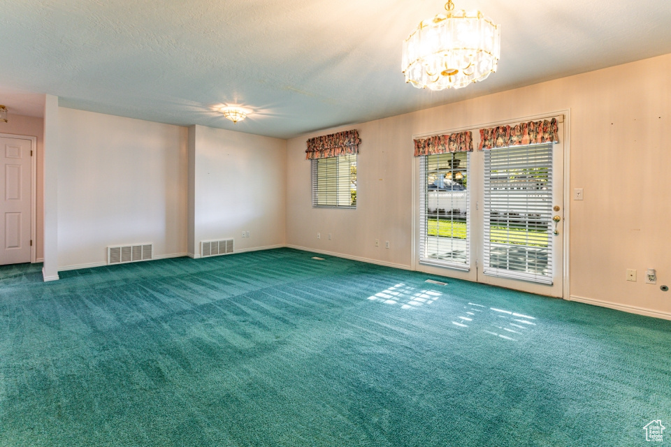 Spare room featuring a chandelier, visible vents, and a healthy amount of sunlight