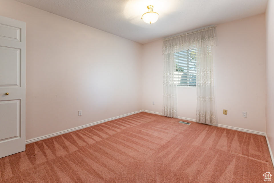 Spare room featuring carpet floors, baseboards, and visible vents
