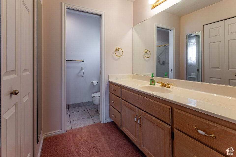 Full bath with tile patterned flooring, vanity, toilet, baseboards, and a closet